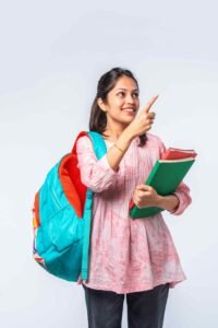 Indian asian young college girl with backpack, laptop, books pointing a sign